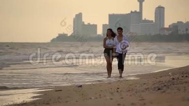 <strong>年</strong>轻的男女赤着脚<strong>携手</strong>走在沙滩上慢动作的女孩和她的男朋友在一起